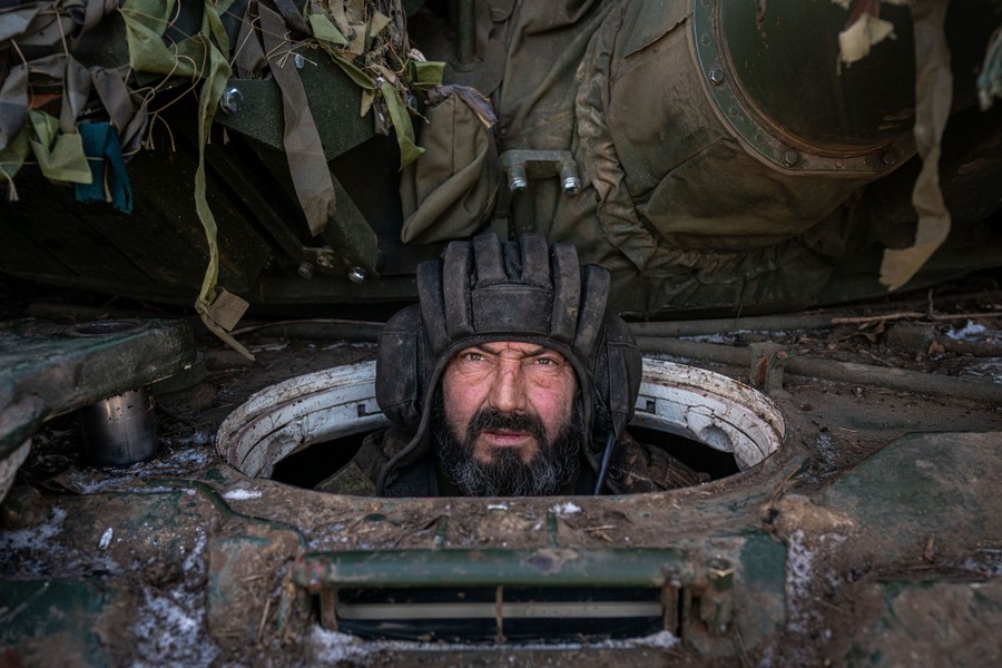 A portrait of a soldier who sits in a military tank with their head poking out of a hole