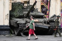 A civilian walks past a tank