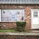 A Confederate flag hangs in the window of a house. 