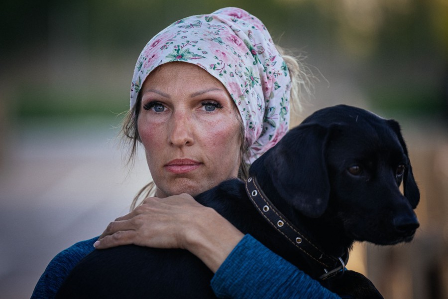 A woman holds on to a black dog.