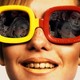 A young woman wearing yellow-red sunglasses reflecting movie characters