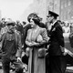 A black-and-white photo of King George VI and Queen Elizabeth drawing crowds in city street