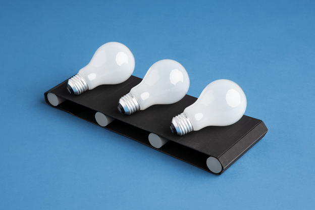 3 light bulbs on black conveyor belt on blue background