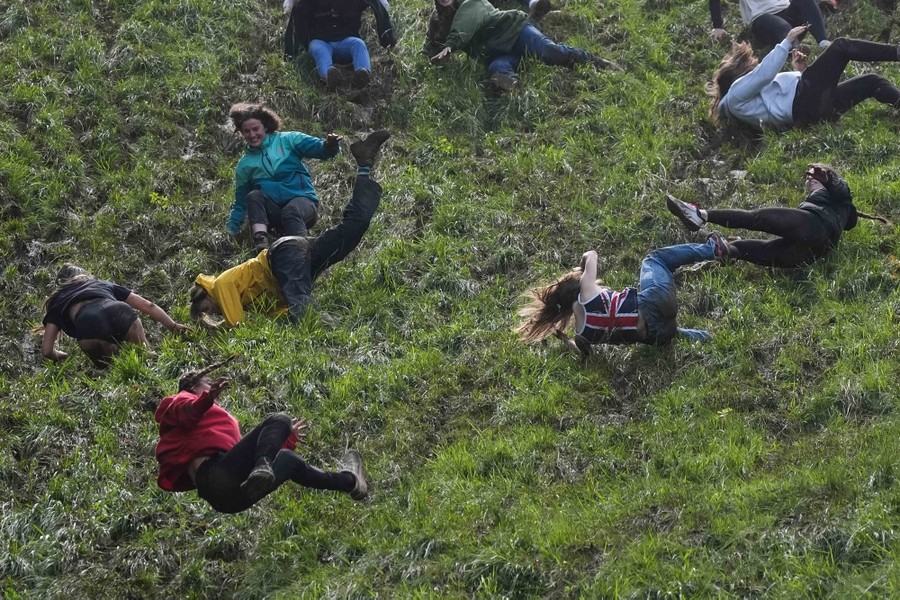 About 10 people tumble down a steep hill.