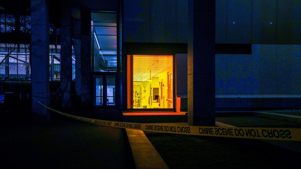 Nighttime photograph of a building at Brown with one room lit up behind police caution tape