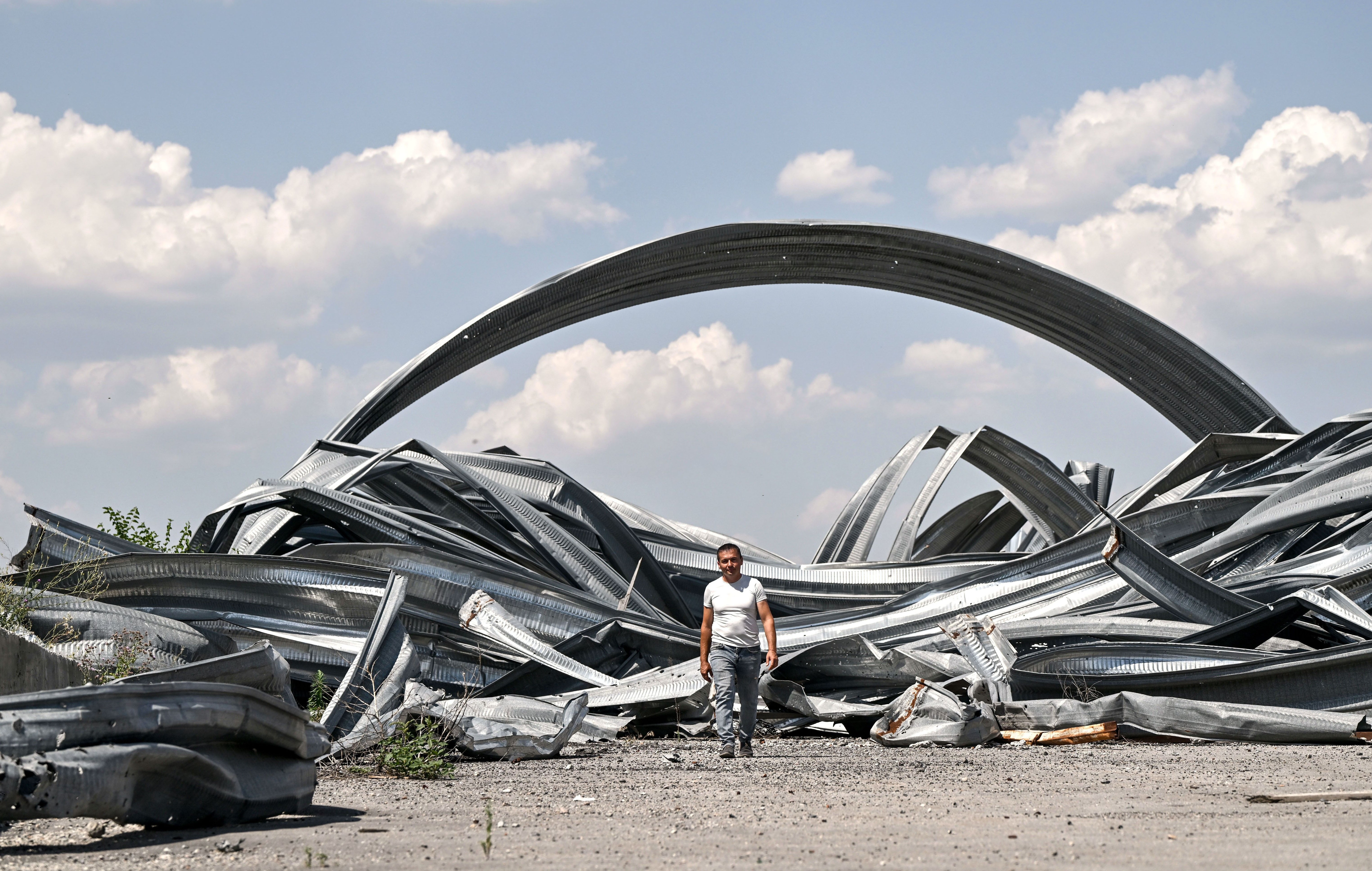 A man walks among the ruins of a hangar granary.