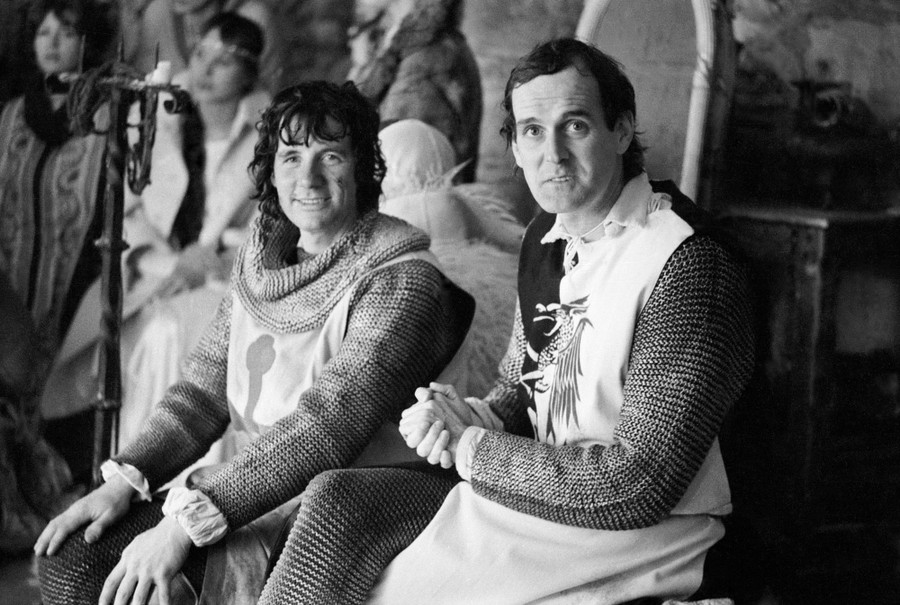 Two members of the Monty Python comedy group sit together in medieval-knight costumes.