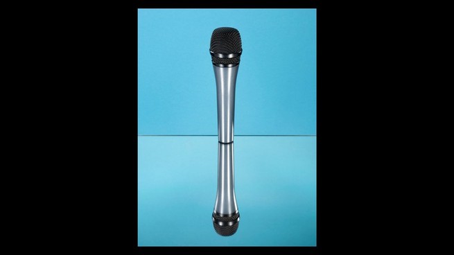 A reflective surface duplicates an image of a microphone against a blue background