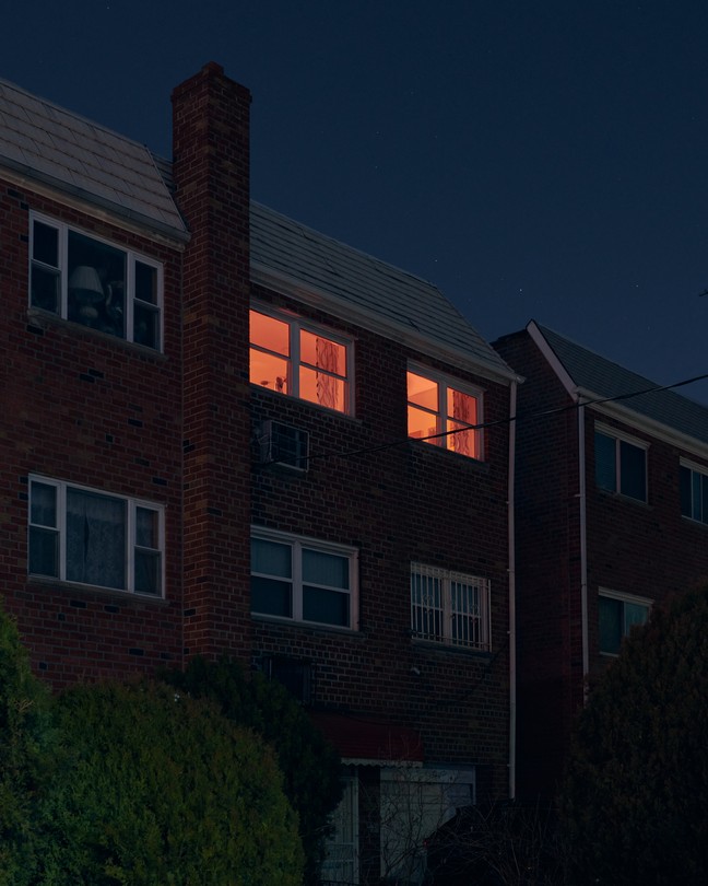 a house in predawn light with windows lit from inside