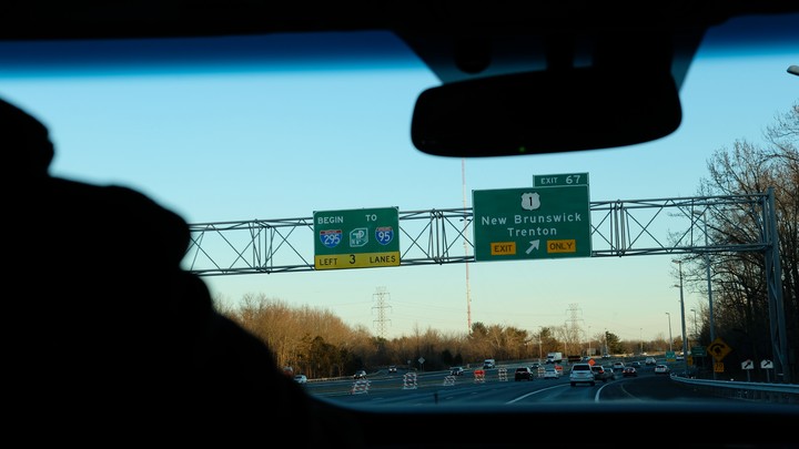 Highway signs for I-95 and I-295 at the exit for New Brunswick in New Jersey, viewed through a car windshield