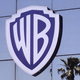 A view of the Warner Brothers logo on a building with a palm tree in the reflection