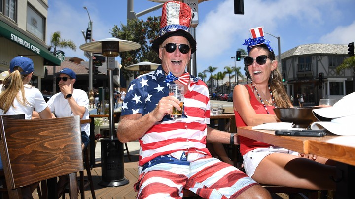 A photo of a man and woman wearing American flag-themed clothing drinking on an outdoor patio