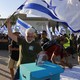 An Israeli military reservist waves a national flag as he drops in a box a signed declaration announcing the suspension of his voluntary reserve duty, in protest of the government's judicial-overhaul bill, in Tel Aviv.