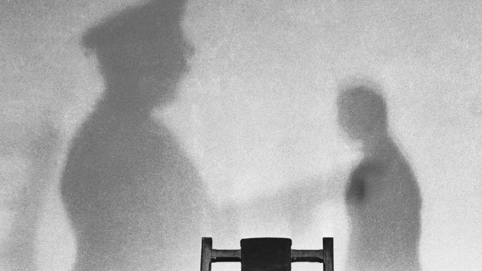Photo of a wall with the shadows of two men in an execution room
