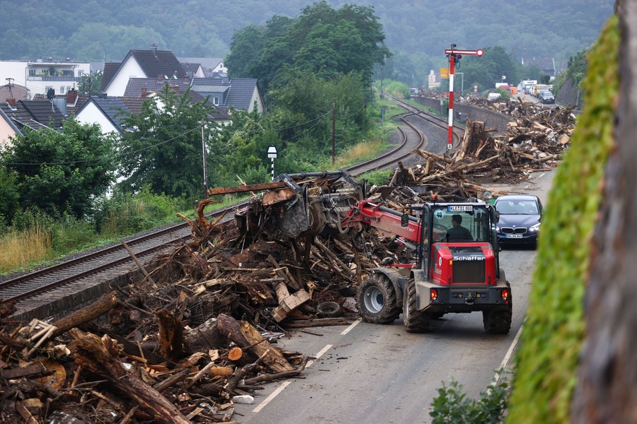 A worker clears broken trees and rubbish on a road.
