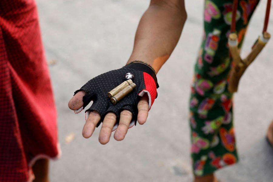 A person holds up two spent bullet casings.