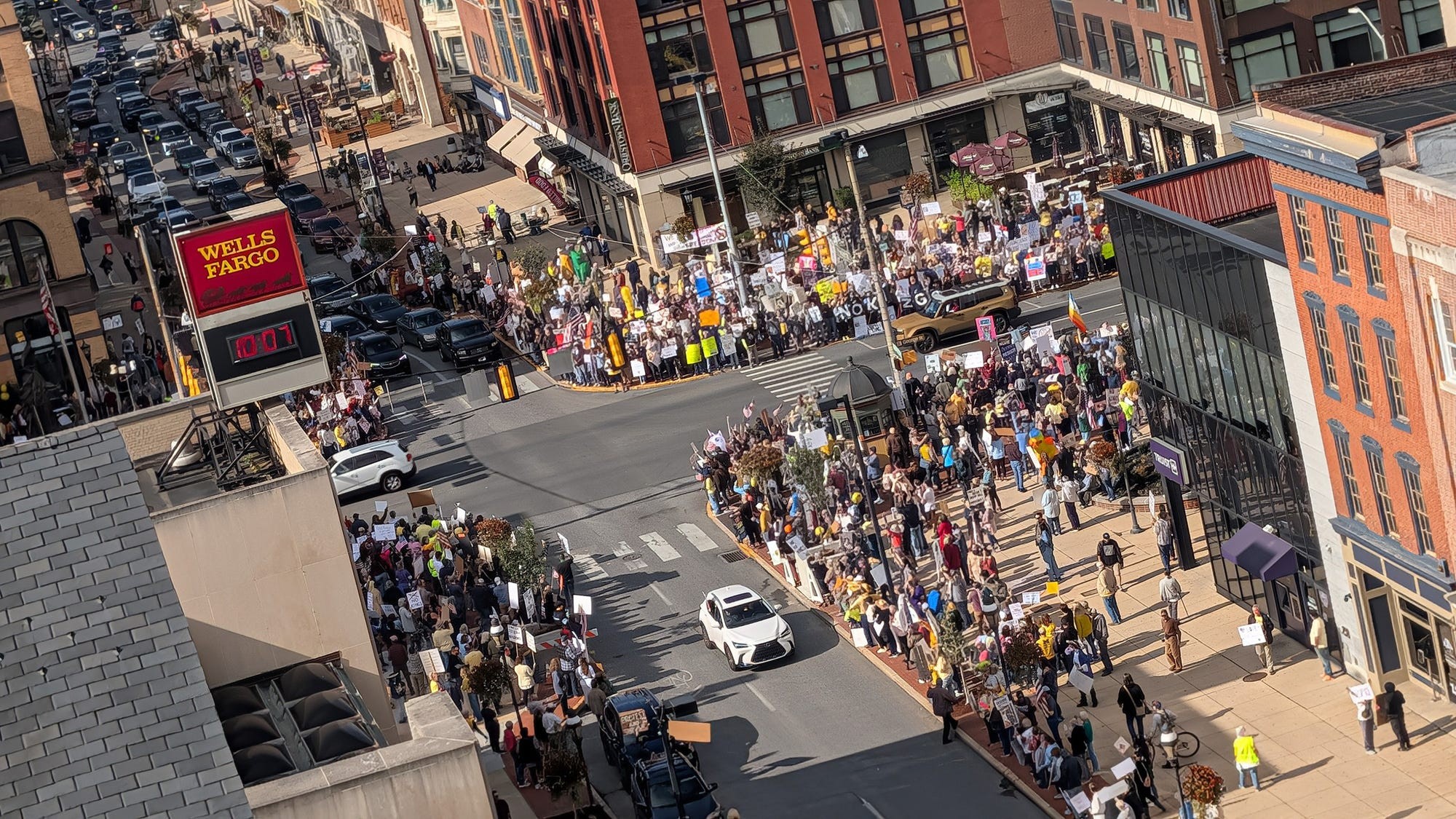 Protesters gather on all four corners of a busy intersection.