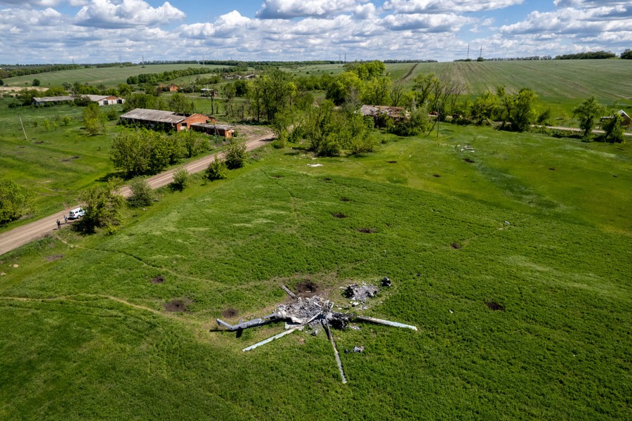 An aerial view of a crashed helicopter in a grassy field.