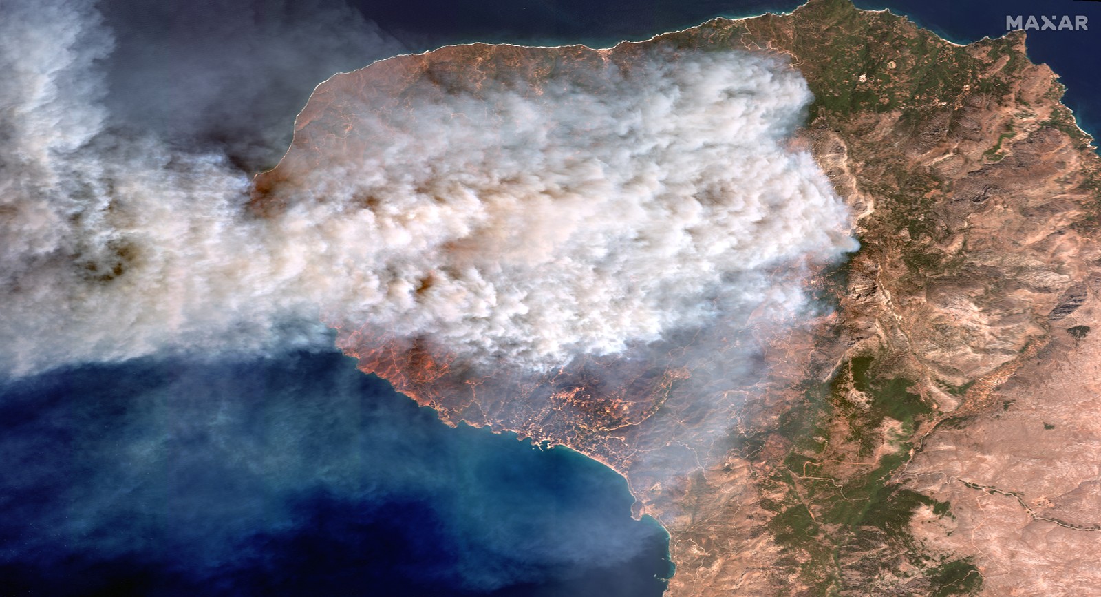 A satellite image shows smoke plumes from wildfires across part of a Greek island.