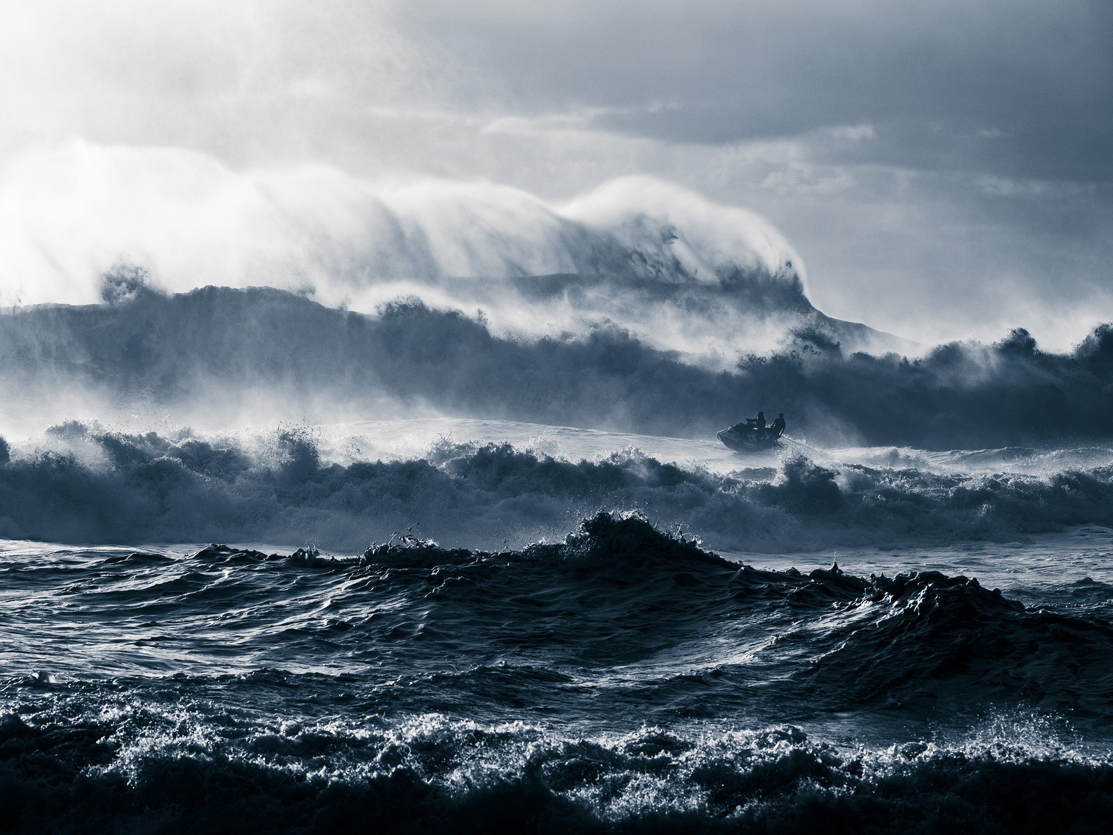 People ride a jet ski through rough surf.