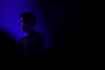 Photograph of Sam Altman in a dark room, his shoulders and face illuminated by a blue light