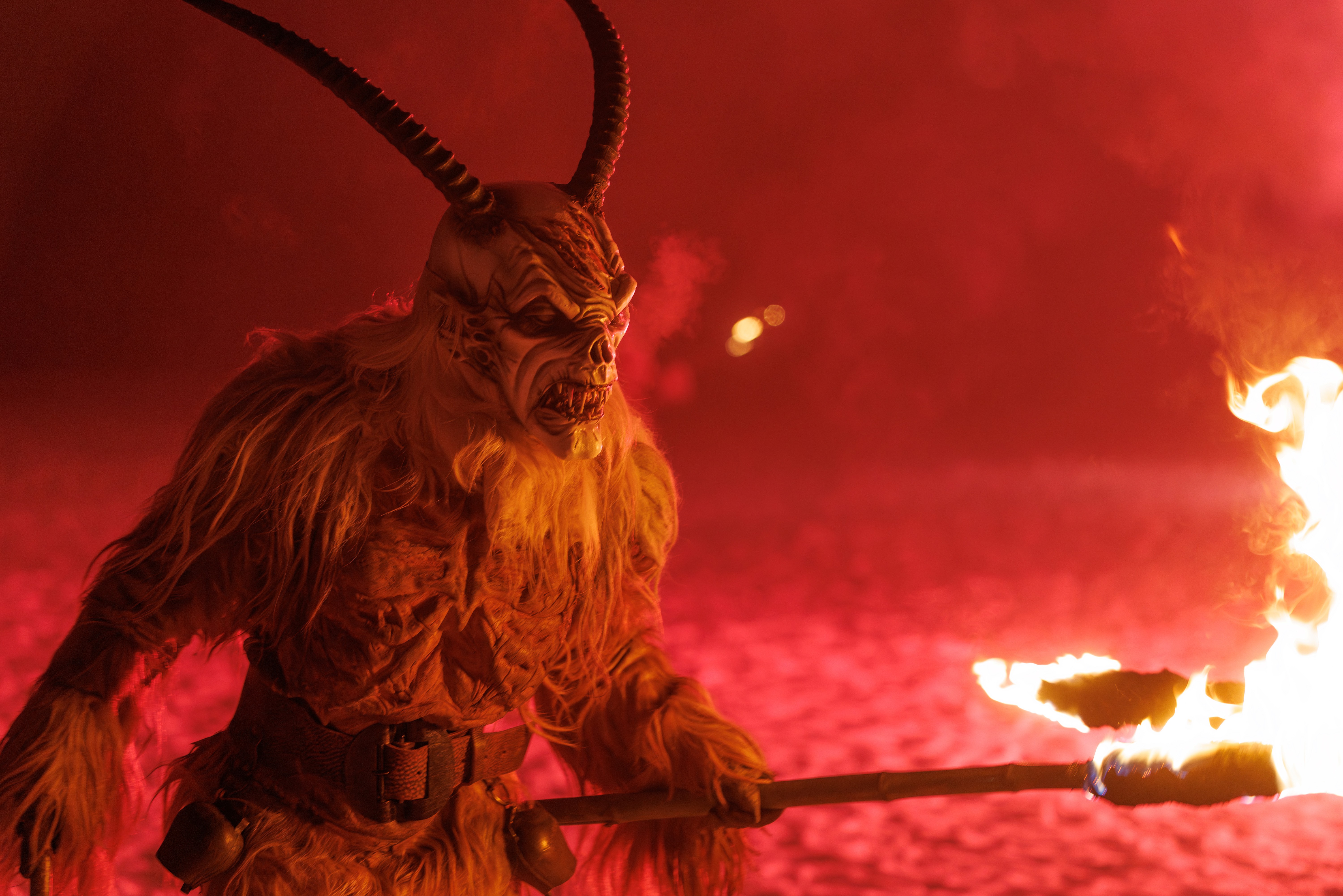 A person dressed as Krampus holds a torch during a performance.