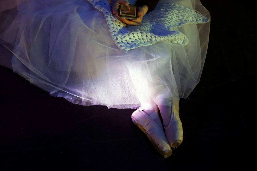 A ballerina looks at her phone during a rehearsal.