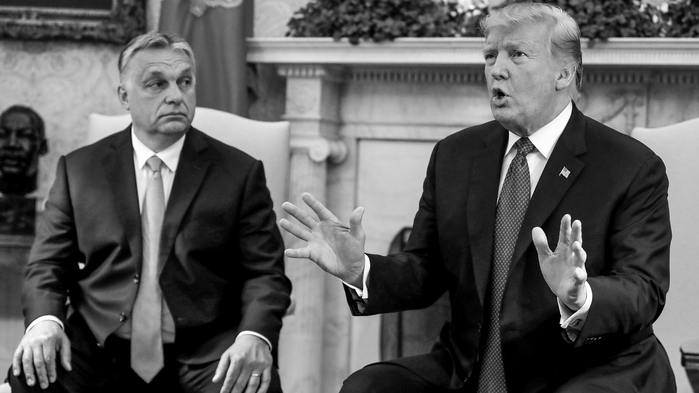 black-and-white photo of Viktor Orbán looking at Donald Trump speaking, both dressed in dark suits and ties, sitting in armchairs in front of fireplace
