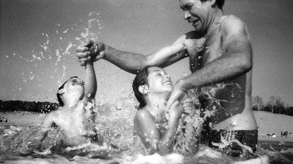 a man struggles as he plays with two children at the beach