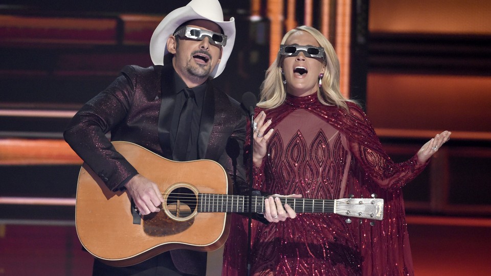 Co-hosts Brad Paisley and Carrie Underwood don eclipse glasses at the 2017 CMAs