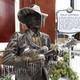 A bronze statue of a bluegrass singer stands outside an auditorium, covered in ice.