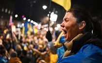A person shouts among a crowd of protesters waving Ukrainian flags.