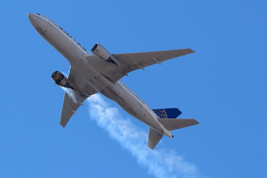 A view looking up toward an aircraft in flight, with its right engine damaged and smoking