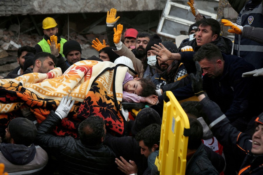 A large group of rescuers carry a girl from a collapsed building following an earthquake.