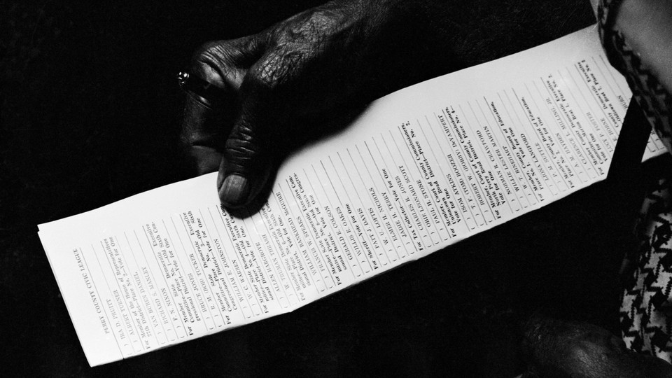 a hand holding a ballot in a black-and-white photo