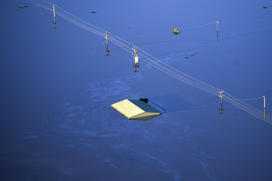 The roof of a single building is seen above floodwater.