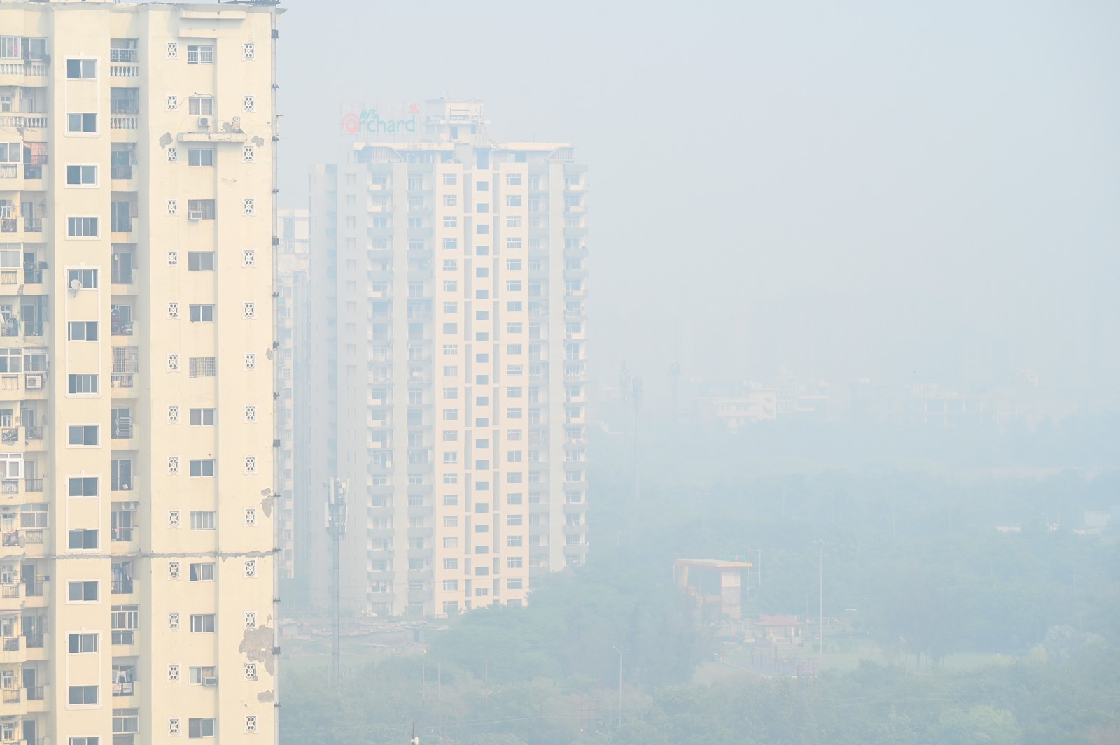 Smog fills the air among tall residential buildings.
