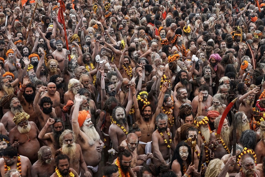 An elevated view of a large crowd of Hindu holy men, many with their arms raised