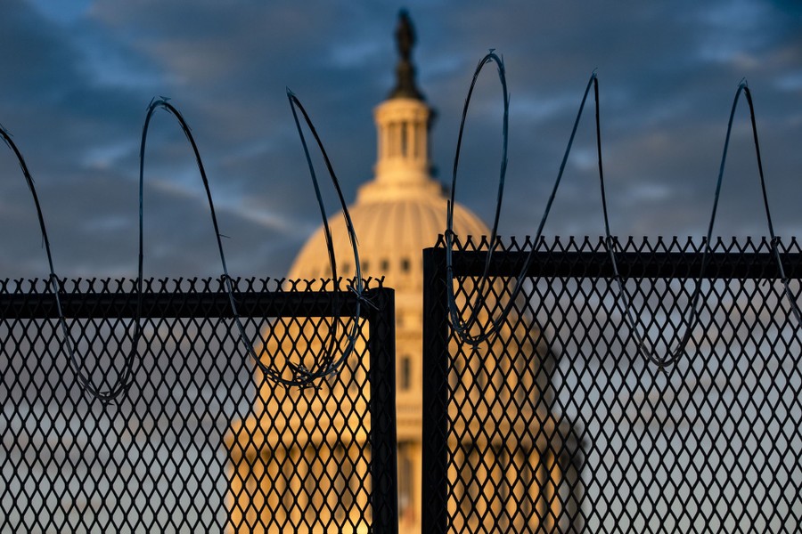 The U.S. Capitol is seen behind a fence with razor wire.