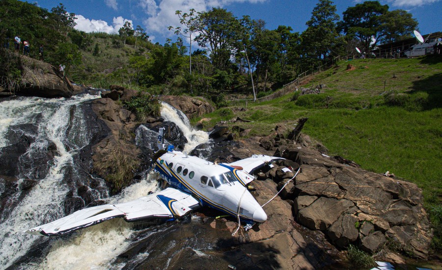 Wreckage of a small airplane rests on rocks along a river.