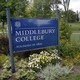 A sign reads "Middlebury College, founded in 1800." A lush green lawn with a tractor fills the rest of the photo.