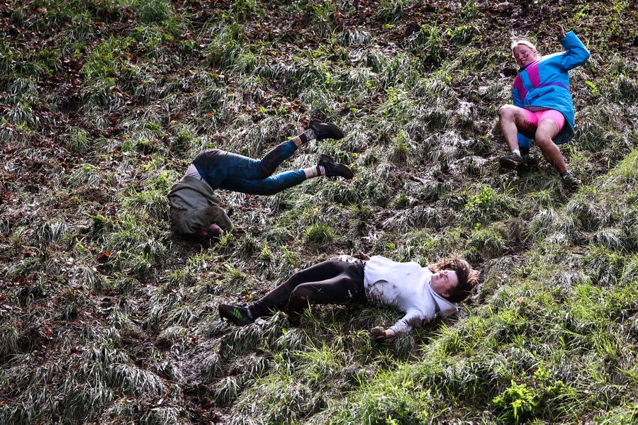 Several racers tumble down a steep, muddy, grassy hill.