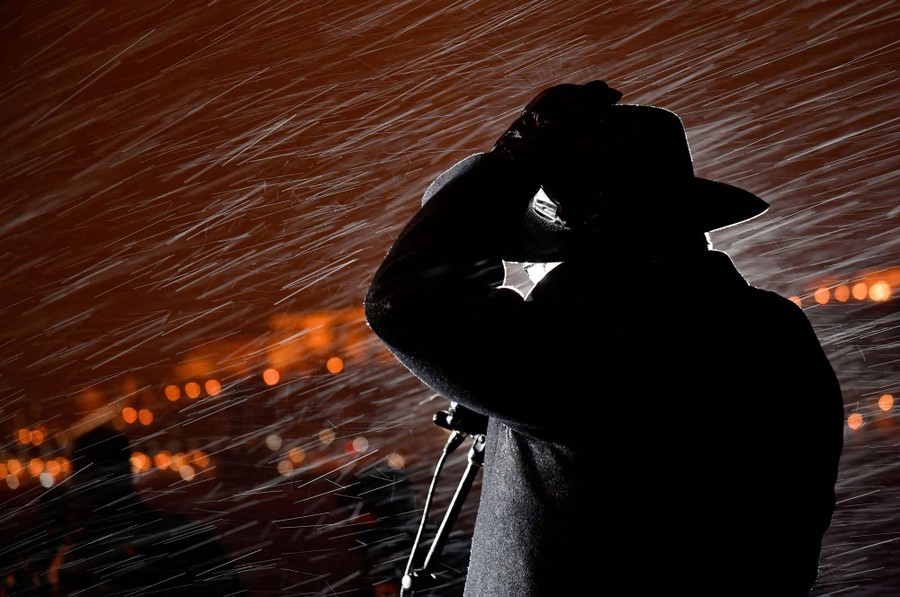 A person stands before a microphone outside during a storm.