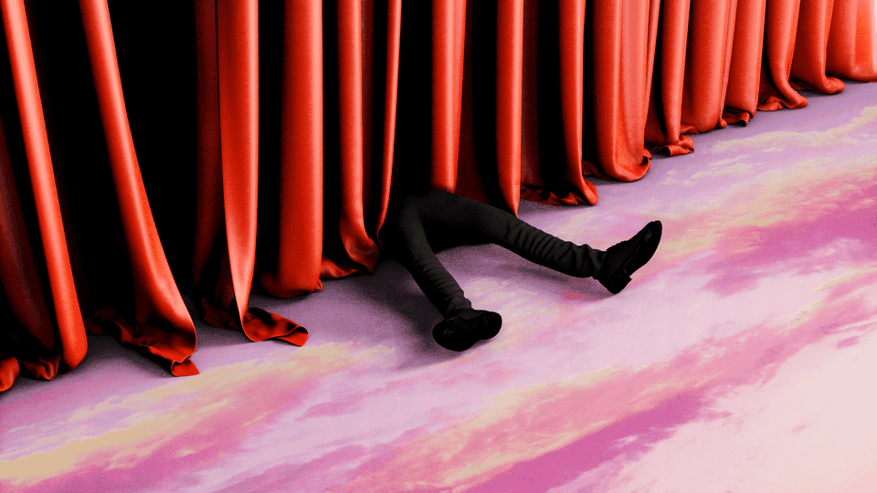 Legs are seen next to a red curtain