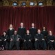 The Supreme Court justices sit in front of a red curtain for a group photo