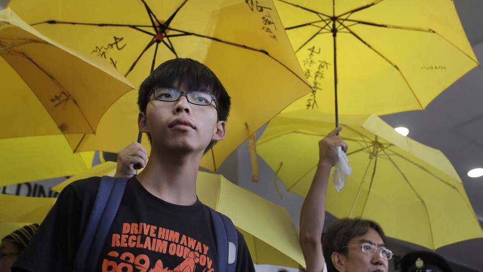 Joshua Wong stands in front of yellow umbrellas, the symbol of the 2014 Hong Kong protests, ahead of a 2015 court hearing.