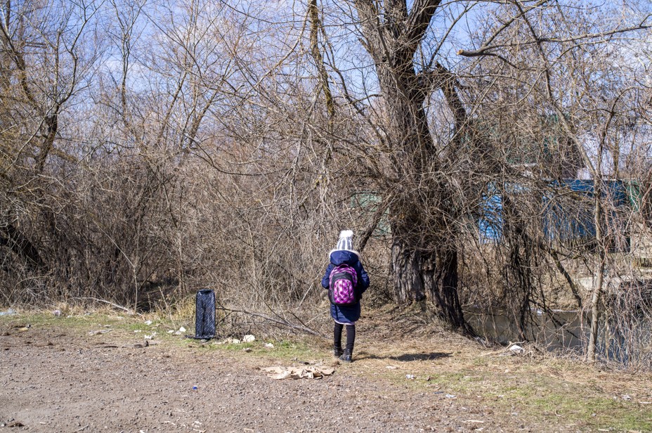 a girls back to camera stands in a field