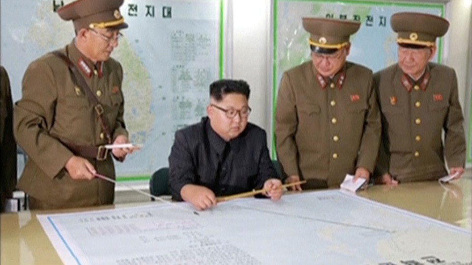 Kim Jong Un and his military advisers examine a large map