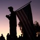 Photo of two men at sunset facing each other, holding American flags