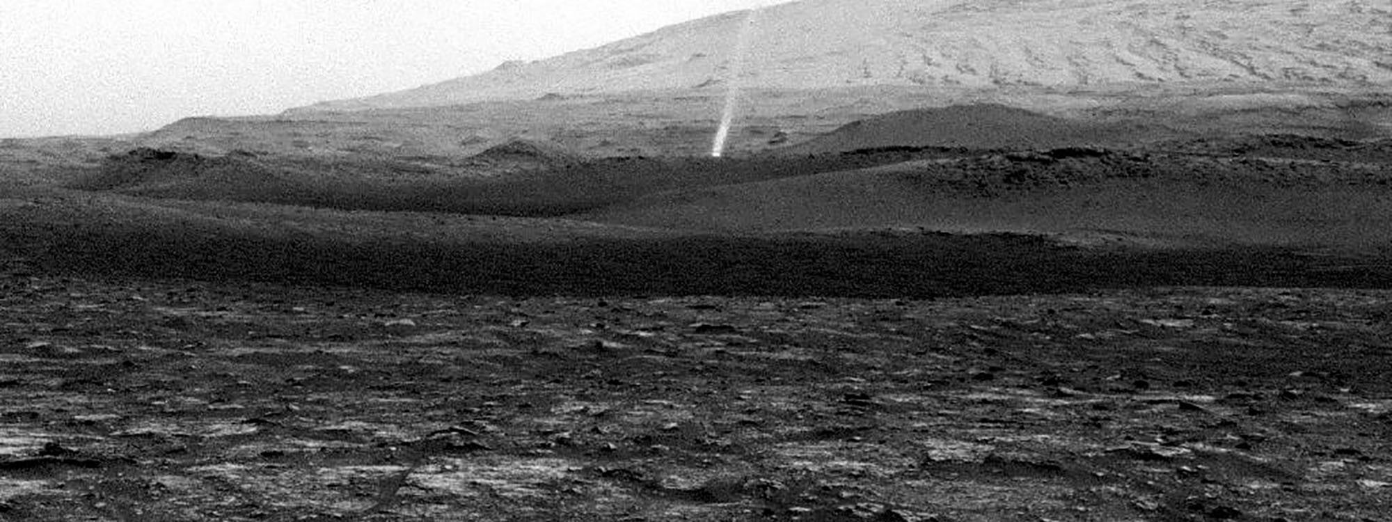 A small dust devil, seen at a distance, on a rocky hillside